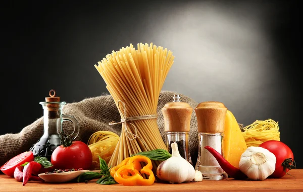 Pasta spaghetti, groenten en kruiden, op houten tafel, op grijze achtergrond — Stockfoto