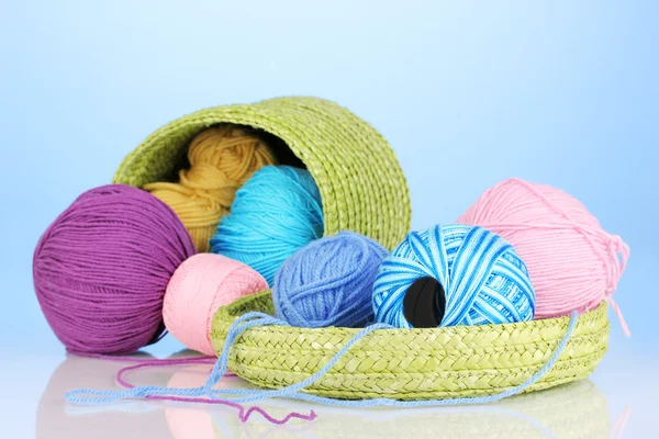 Colorful yarn for knitting in green basket on blue background — Stock Photo, Image