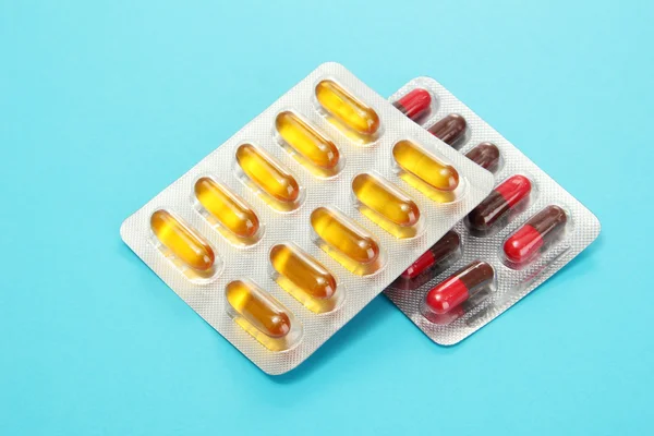 Capsules packed in blisters, on blue background — Stock Photo, Image