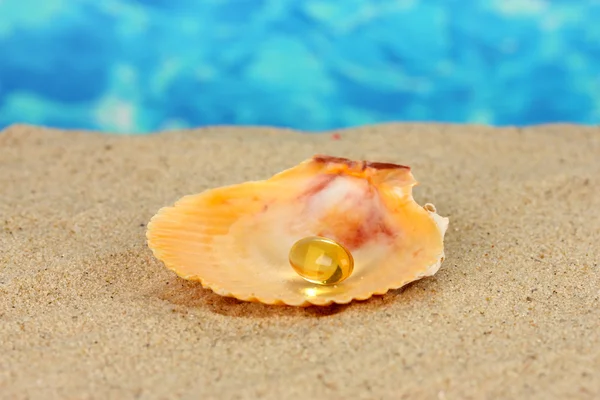 Rybí olej v shellu v písku na modrém pozadí — Stock fotografie