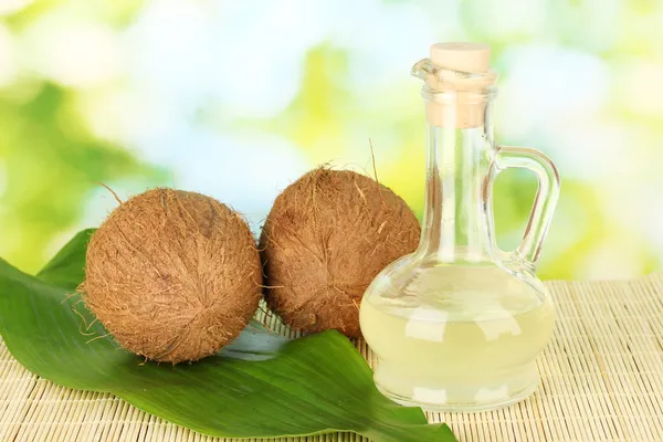 Karaff med kokosolja och kokosnötter på grön bakgrund — Stockfoto