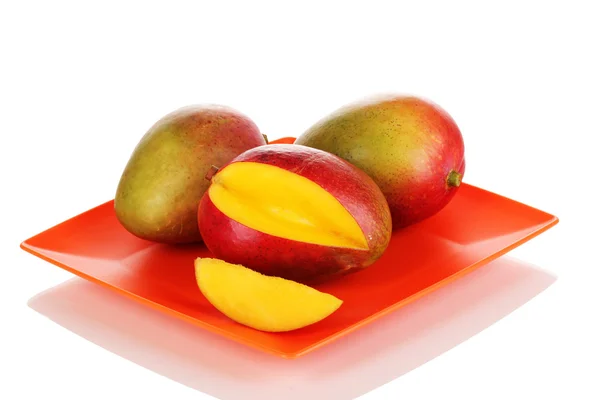 Ripe appetizing mango on red plate isolated on white — Stock Photo, Image
