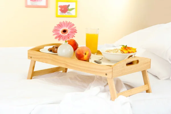 Holztablett mit leichtem Frühstück auf dem Bett — Stockfoto
