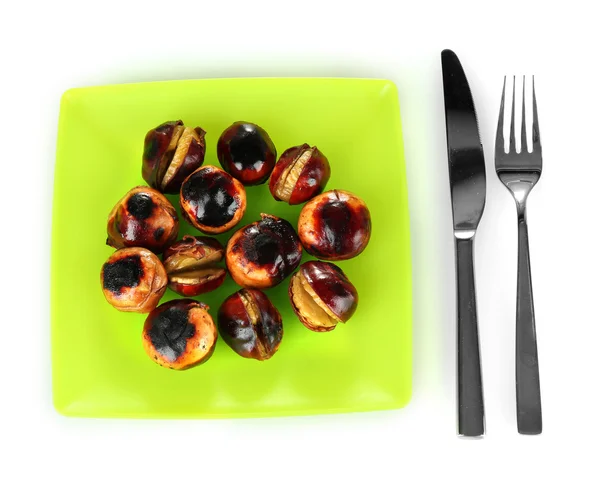 Roasted chestnuts in the green plate with fork and knife isolated on white — Stock Photo, Image