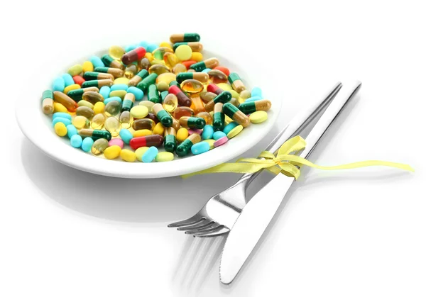 Colorful capsules and pills on plate with fork and knife, isolated on white — Stock Photo, Image