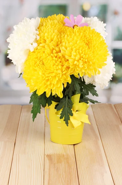 Krásné chryzantémy v vědro na dřevěný stůl na pozadí okna — Stock fotografie