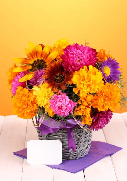 Belo buquê de flores brilhantes com nota de papel na mesa de madeira no fundo amarelo — Fotografia de Stock