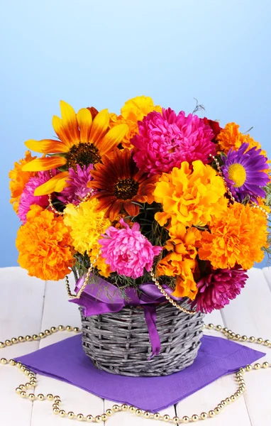 Mooi boeket van heldere bloemen op houten tafel op blauwe achtergrond — Stockfoto