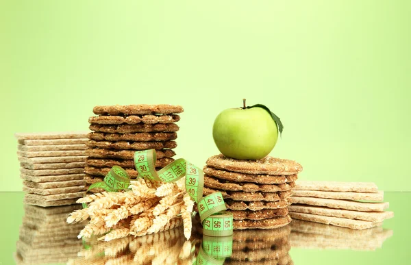 Leckeres Knäckebrot, Apfel, Maßband und Ohren, auf grünem Hintergrund — Stockfoto