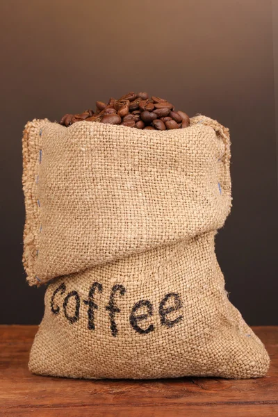 Coffee beans in bag on table on dark background — Stock Photo, Image