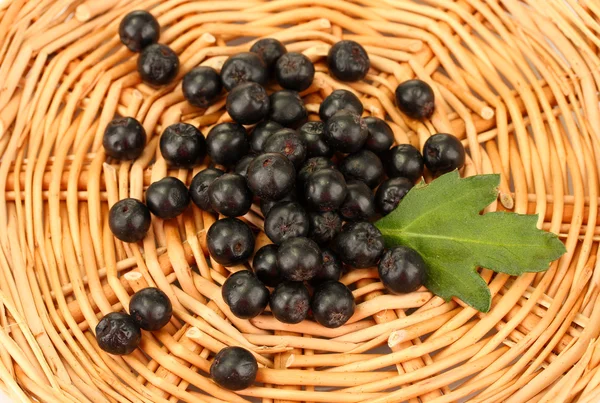 Chokeberry with green leaf on wicker mat close-up — Stock Photo, Image