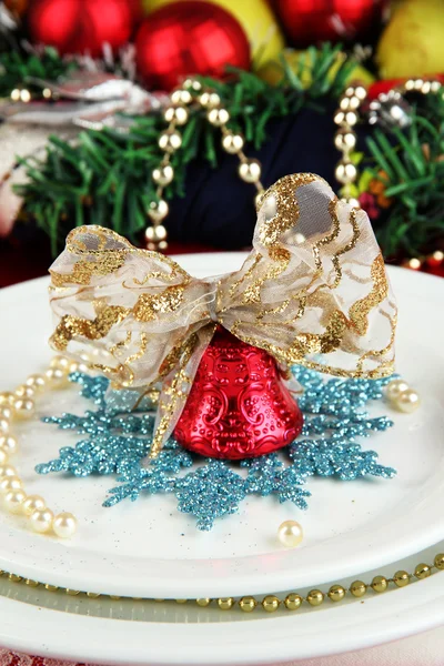 Pequeña campana de Navidad en un plato al servir fondo de la mesa de Navidad de cerca —  Fotos de Stock