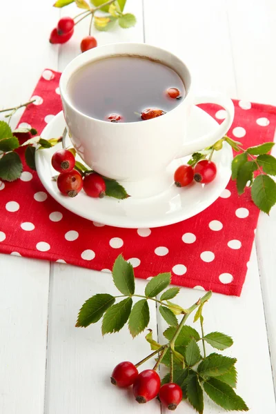 Taza de té con rosas de la cadera, sobre mesa de madera —  Fotos de Stock