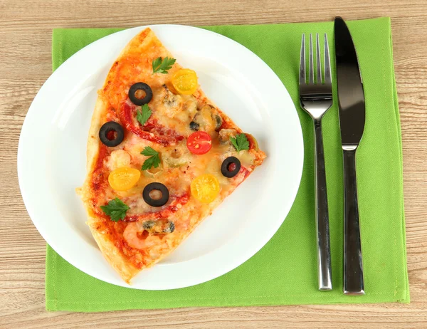 Assiette avec une tranche de délicieuse pizza sur fond en bois — Photo