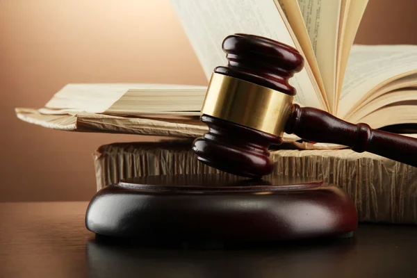 Wooden gavel and books on wooden table,on brown background — Zdjęcie stockowe