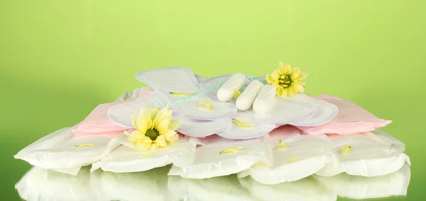 Various types of sanitary pads and tampons on green background close-up — Stock Photo, Image