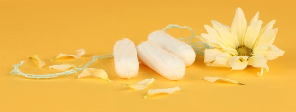 Cotton tampons with yellow flower on orange background close-up — Stock Photo, Image