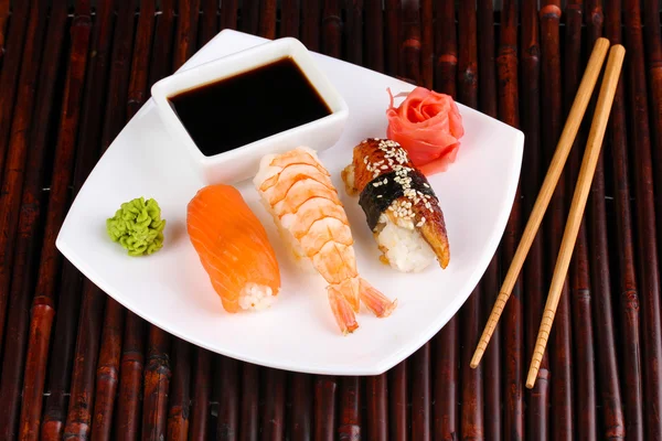 Pyszne sushi serwowane na tabliczce na mat bambusowych — Zdjęcie stockowe