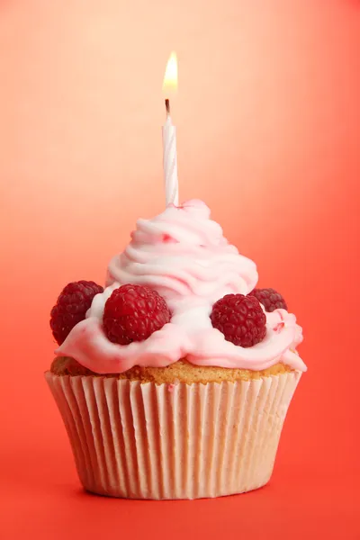 Tasty birthday cupcake with candle, on red background — Stock Photo, Image