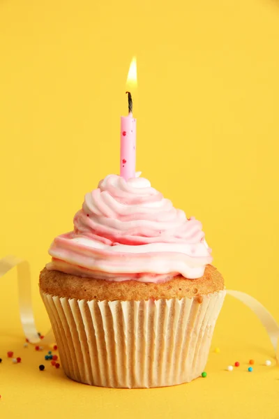 Chutné narozeninové košíček s svíčkou, na žlutém podkladu — Stock fotografie