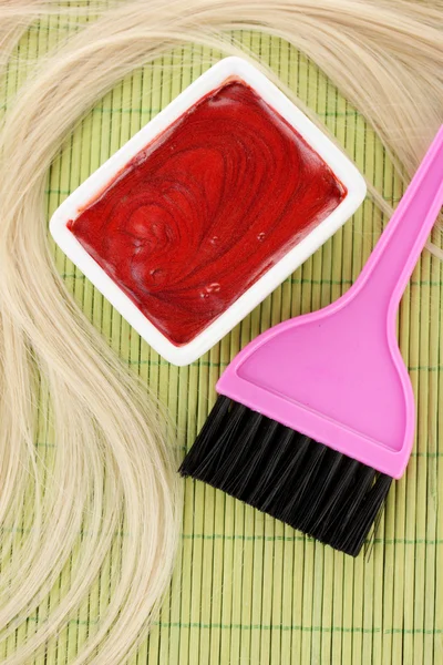 Tintura de cabelo na tigela e escova para coloração de cabelo no tapete de bambu verde, close-up — Fotografia de Stock