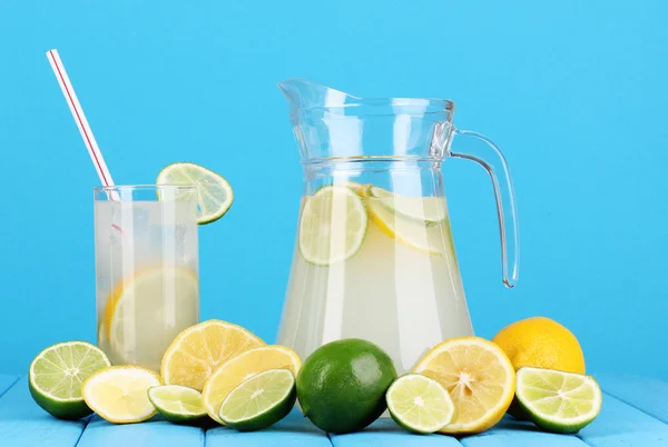 Citrus limonata in brocca e vetro di agrumi intorno su tavolo di legno su sfondo blu — Foto Stock