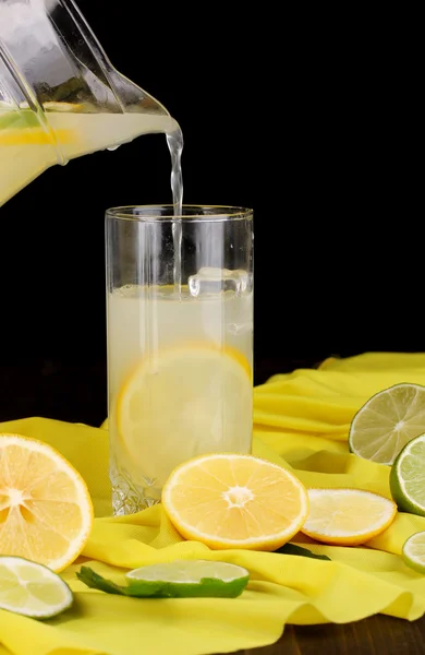 Citrus saft i glas och tillbringare med citrus runt på gult tyg på träbord närbild — Stockfoto