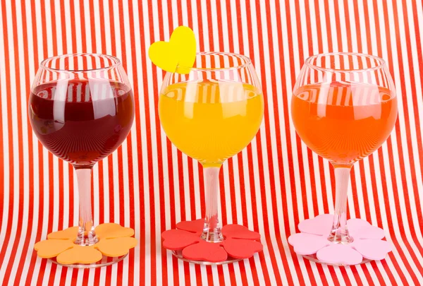 Πολύχρωμο κοκτέιλ με φωτεινή διακόσμηση για ποτήρια σε κόκκινο φόντο με ρίγες — Φωτογραφία Αρχείου