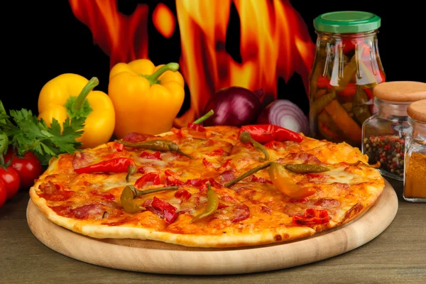 Вкусная пицца пепперони с овощами на деревянной доске на фоне пламени — стоковое фото