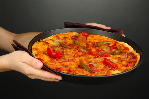 Handen met pepperoni pizza in pan op grijze achtergrond — Stockfoto