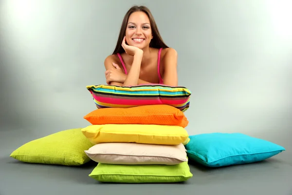 Beautiful young girl with pillows on grey background — Stock Photo, Image