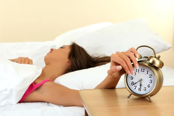 Young beautiful woman in bed and alarm clock — Stock Photo, Image