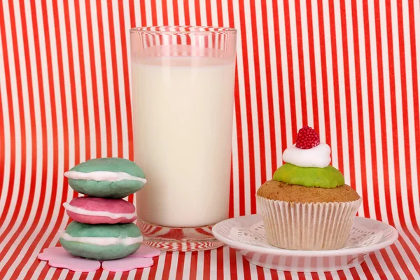 Glass of fresh new milk with confectionery on red striped background — Stock Photo, Image