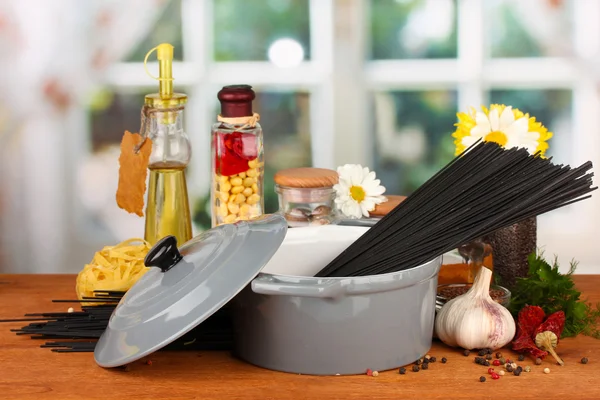 Espaguete na panela na mesa de madeira no fundo brilhante — Fotografia de Stock