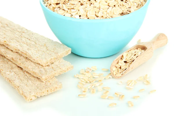 Tigela azul cheia de flocos de aveia com colher de madeira e biscoitos de aveia isolados em branco — Fotografia de Stock