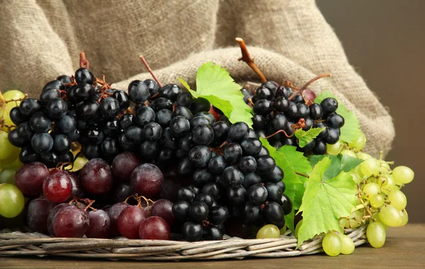 Ассортимент спелых сладких винограда в корзине, на коричневом фоне — стоковое фото