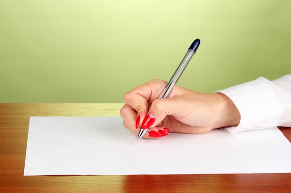 Mãos a escrever sobre papel sobre fundo verde — Fotografia de Stock