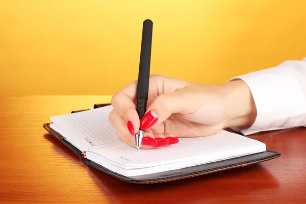 Χέρι εισέλθετε σημειωματάριου στο ξύλινο τραπέζι σε φόντο χρώμα — Φωτογραφία Αρχείου