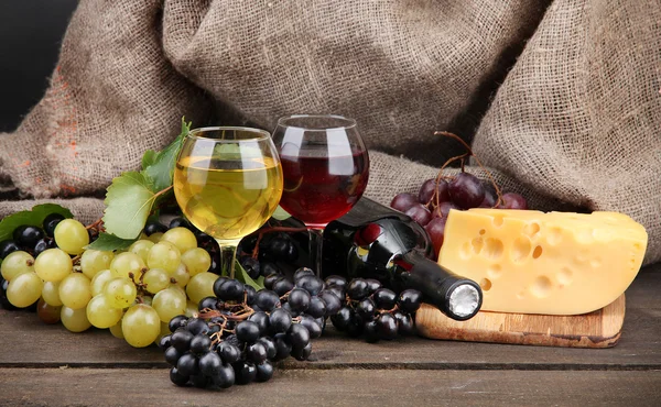 Bottiglia e calici di vino, formaggio e uva su fondo grigio — Foto Stock