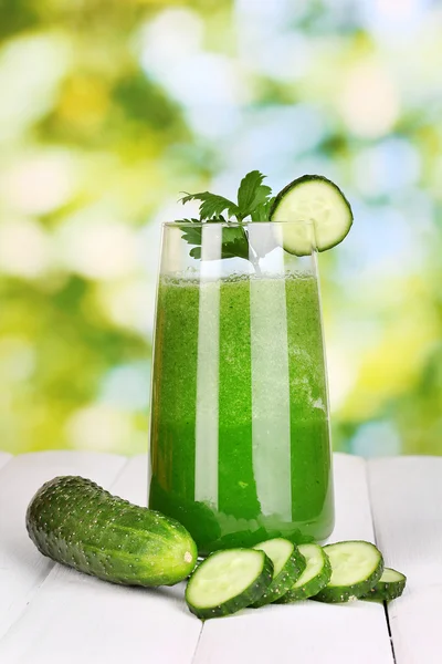 Glass of cucumber juice on wooden table, on green background — Stock Photo, Image