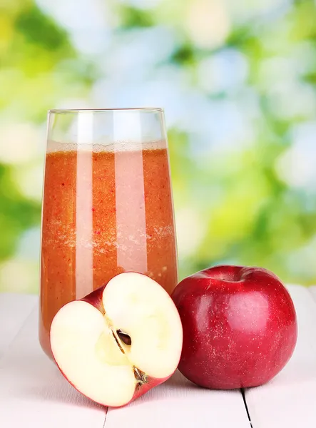 Glass of fresh apple juice on wooden table, on green background — Stock Photo, Image