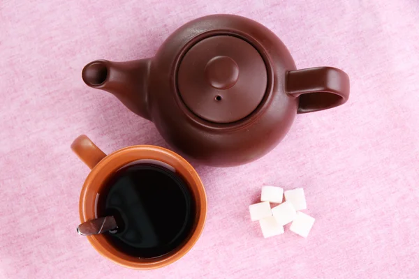 Top view of cup of tea and teapot on pink tablecloths — Stock Photo, Image