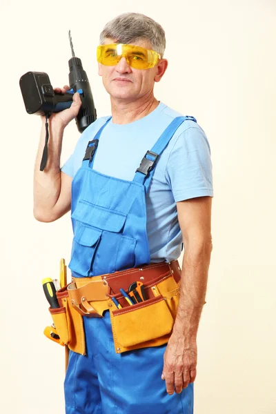 Builder with drill on wall background — Stock Photo, Image