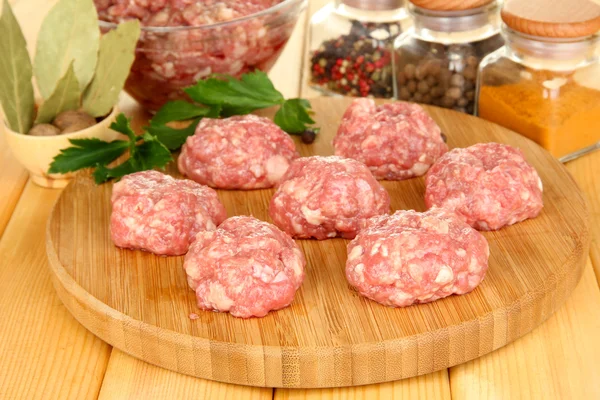 RAW köttbullar med kryddor på träbord — Stockfoto