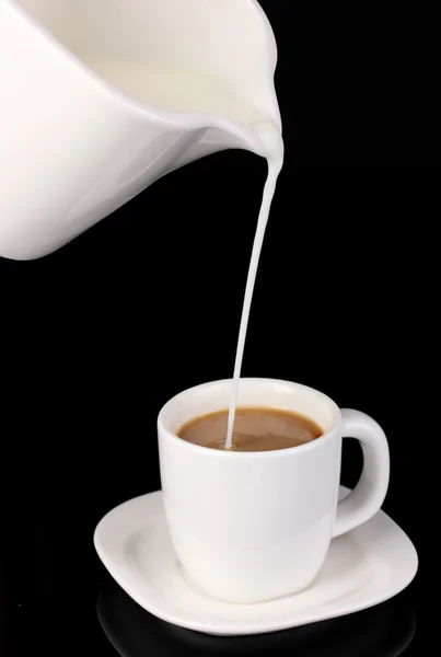 Delicate cream poured into cup of coffee isolated on black — Stock Photo, Image