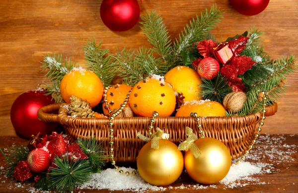 Composição de natal em cesta com laranjas e abeto, sobre fundo de madeira — Fotografia de Stock