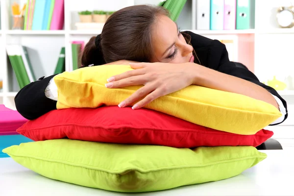 Mujer de negocios cansada con almohadas sentadas a la mesa y duerme — Foto de Stock