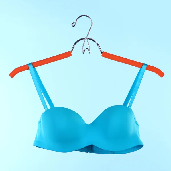Elegant bra on hanger on blue background — Stock Photo, Image