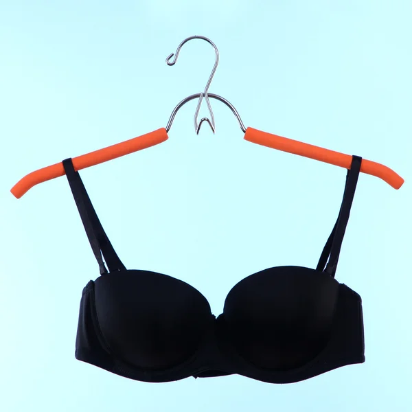 Elegant bra on hanger on blue background — Stock Photo, Image