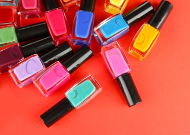 Group of bright nail polishes, on red background clipart